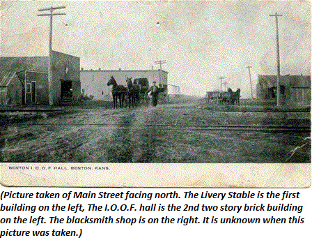 Picture taken of Main Street facing north. The Livery Stable is the first building on the left, the I.O.O.F. half is the 2nd two story brick building on the left. The blacksmith shop is on the right. It is unknown when this picture was taken.